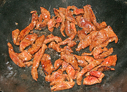 Beef stir-frying in wok.