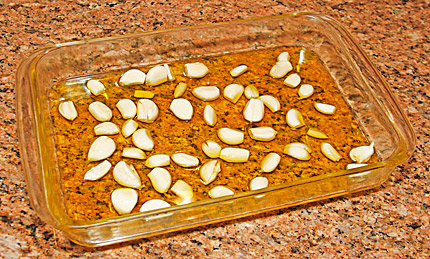 Photo of a baking dish with olive oil and about 40 cloves of garlic, for roasting.