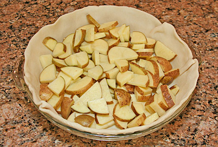 Photo of pie preparation, showing bottom layer of sliced potatoes.